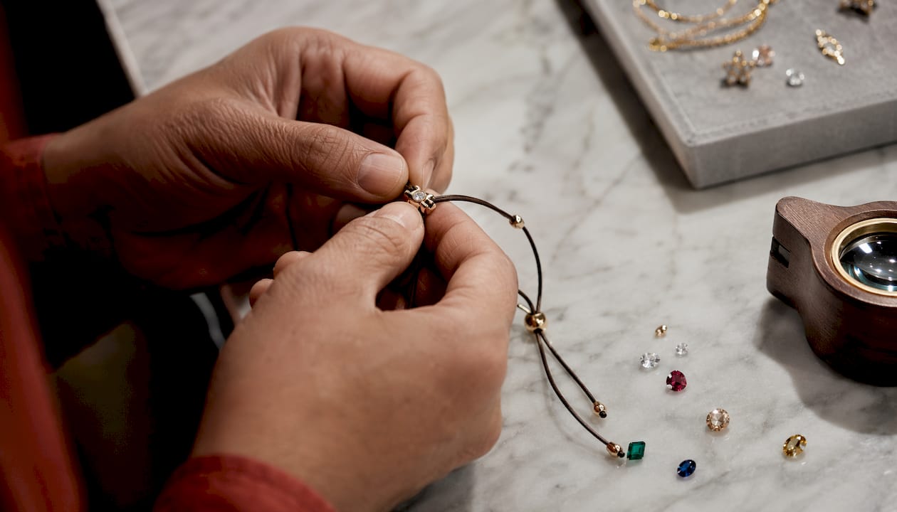 Jeweler setting diamond on luxury gold string bracelet