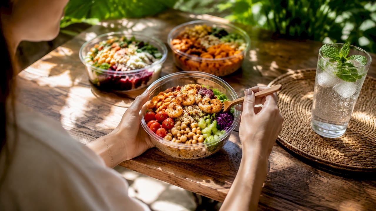 Top-down view of high-protein deli salads with hands