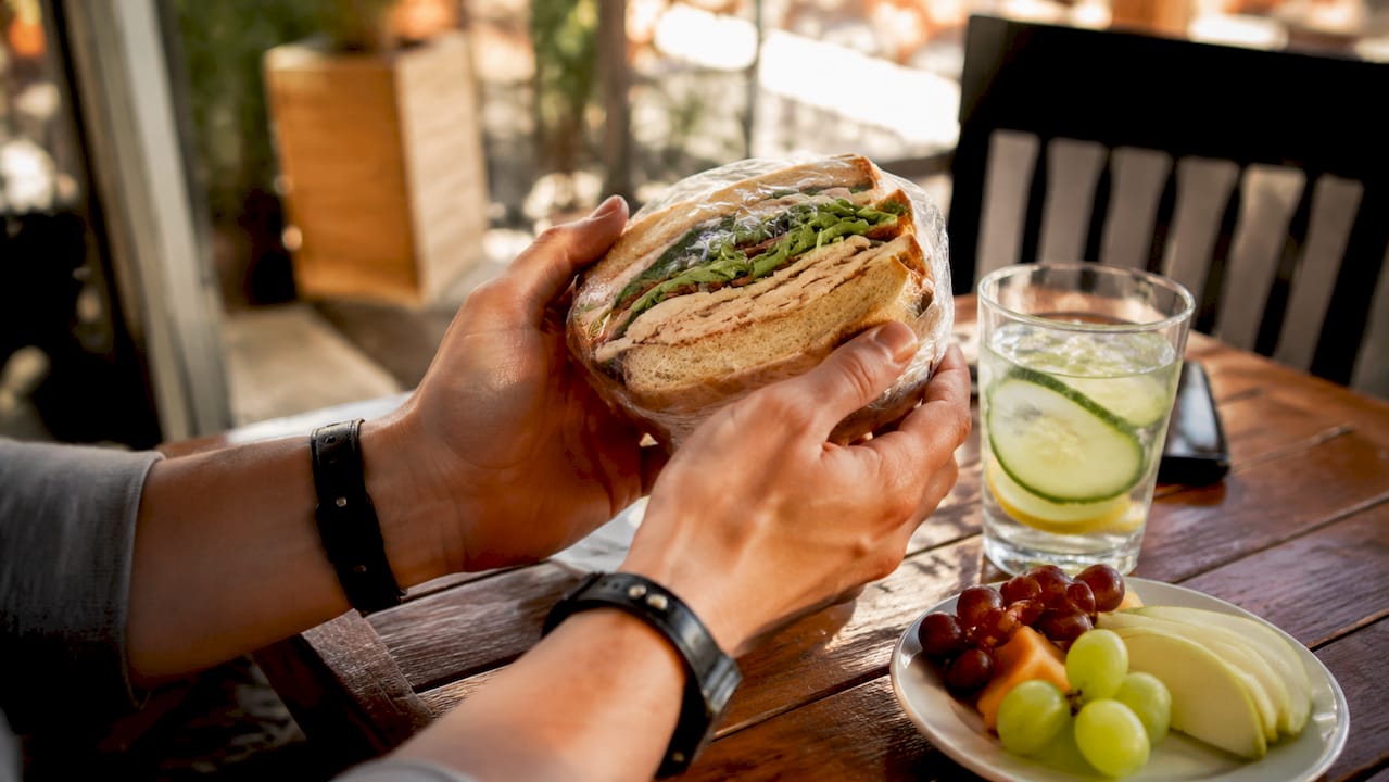 Hands holding deli sandwich at café table
