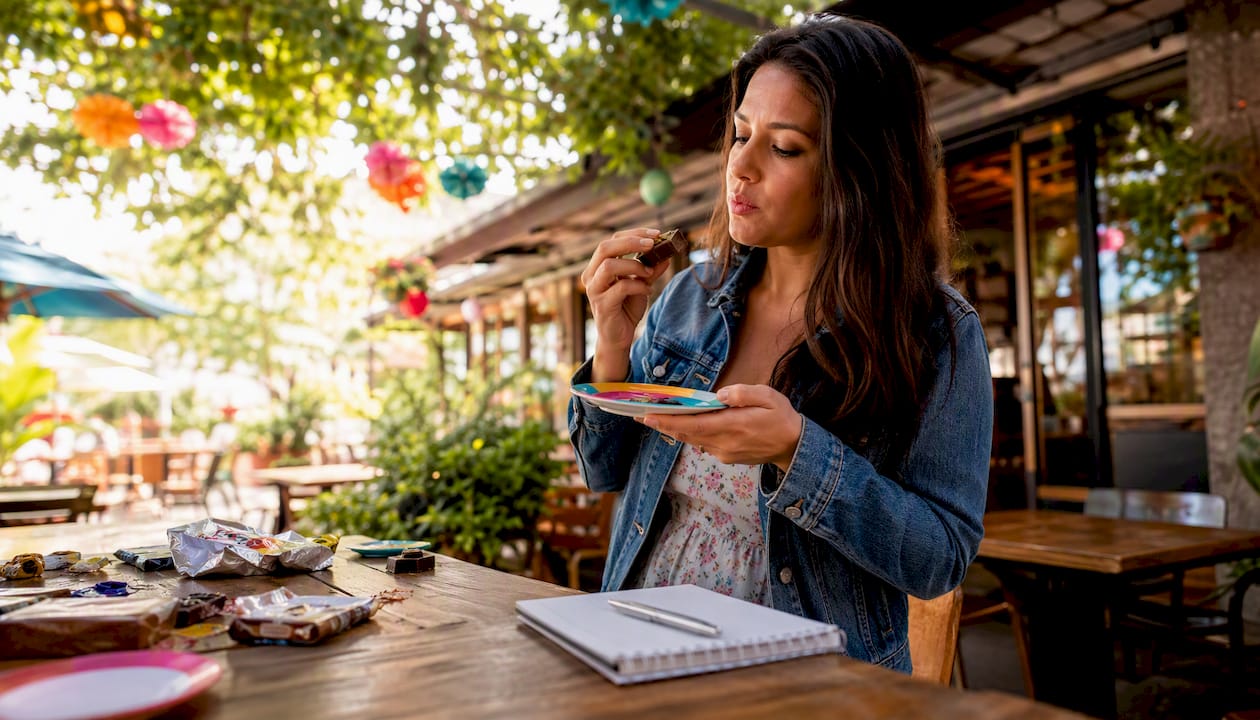 Woman tasting and evaluating candy bars at kitchen counter
