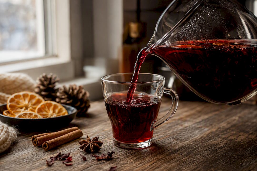Pouring spiced sorrel tea into glass mug