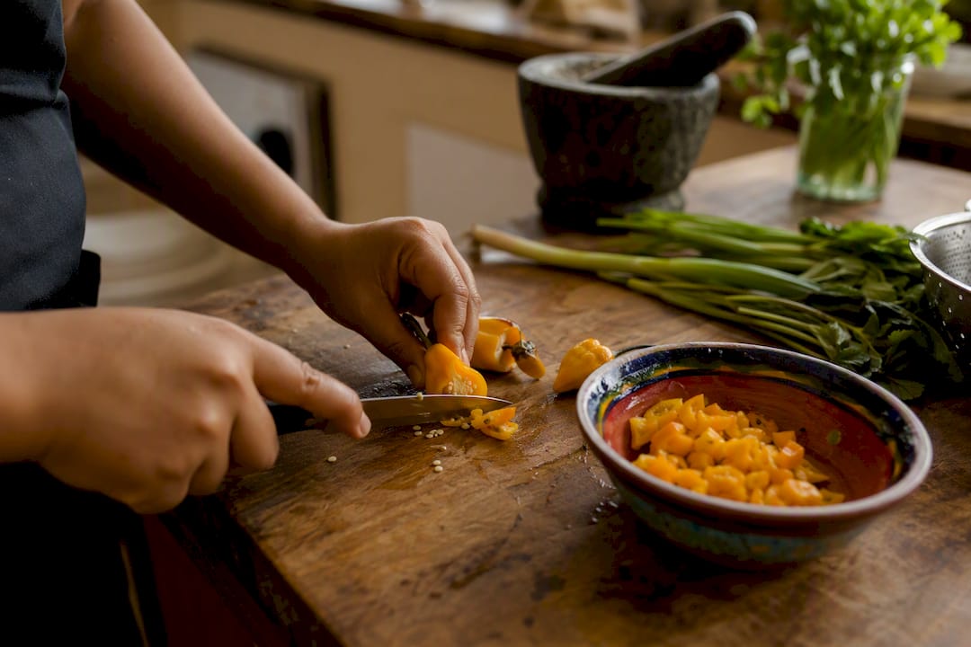 Hands slicing Scotch bonnet hot pepper