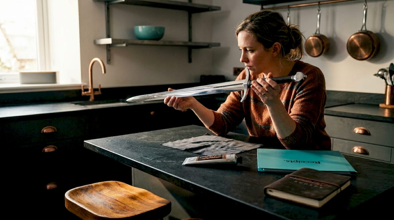 Woman inspecting replica sword at kitchen island