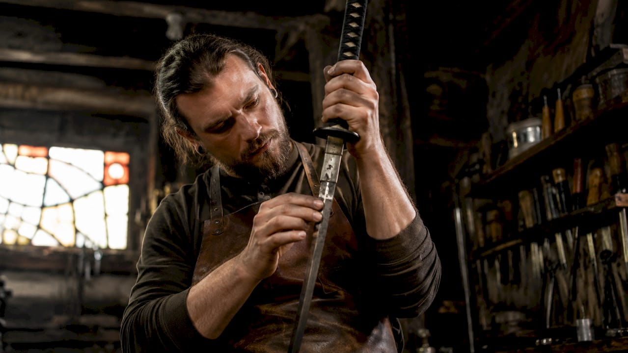 Craftsman inspecting katana replica sword at workshop