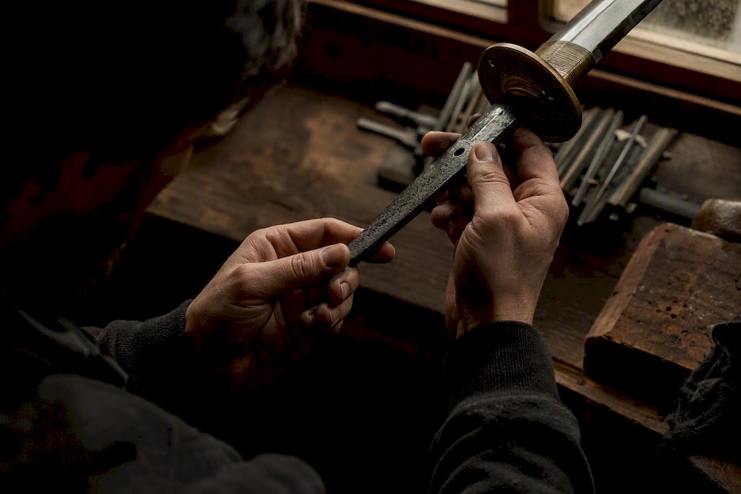 Hands inspecting sword tang detail