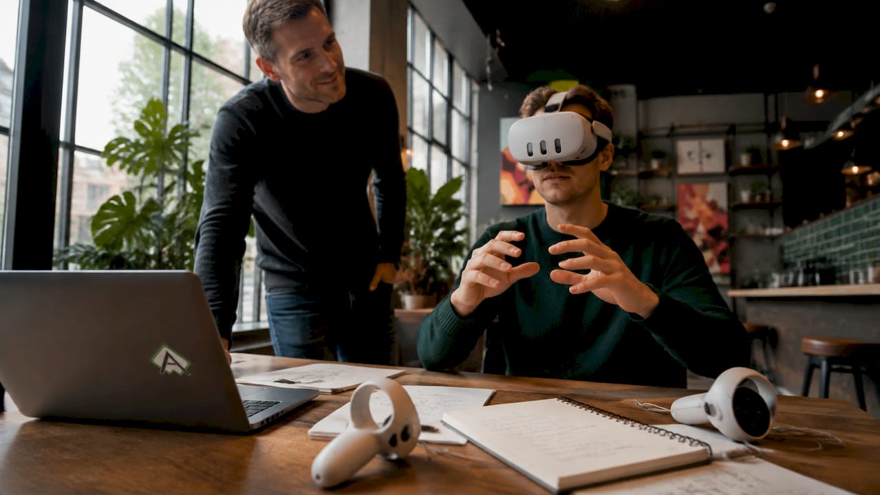 Ein Ausbilder schaut einem Azubi bei einer VR-Schulung über die Schulter.