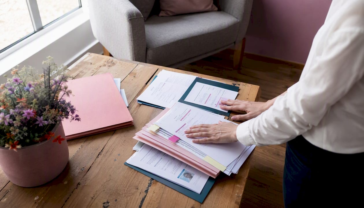 Des mains trient et classent des dossiers de recrutement médical sur un bureau.
