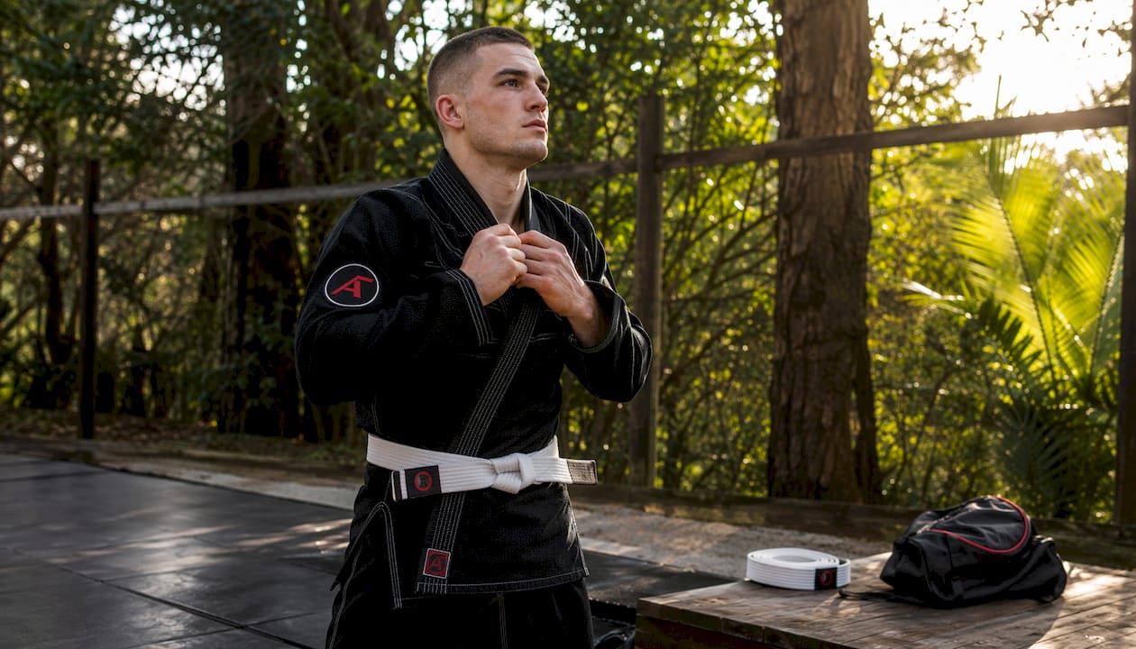 Male athlete adjusting custom BJJ gi indoors