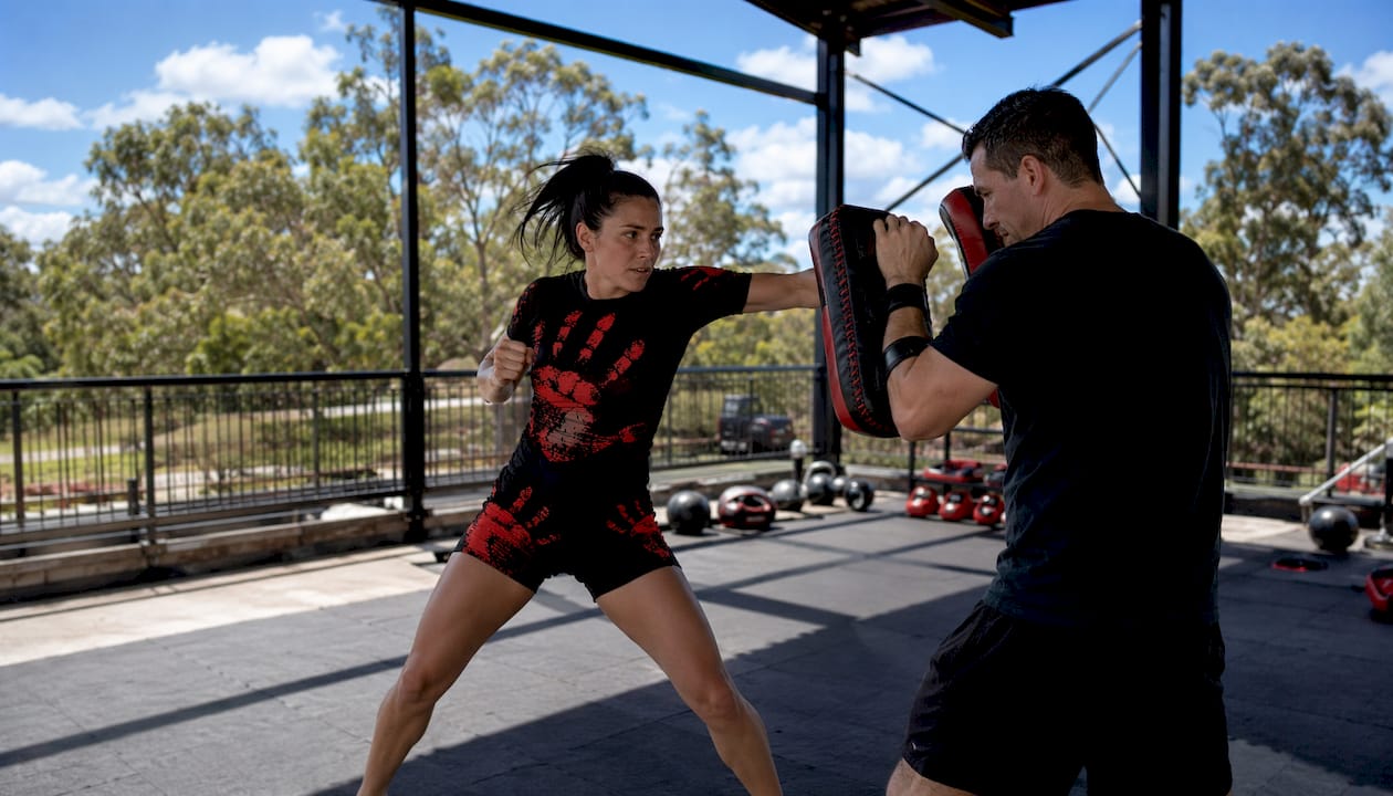 Female MMA athlete striking pads in Combatra shorts