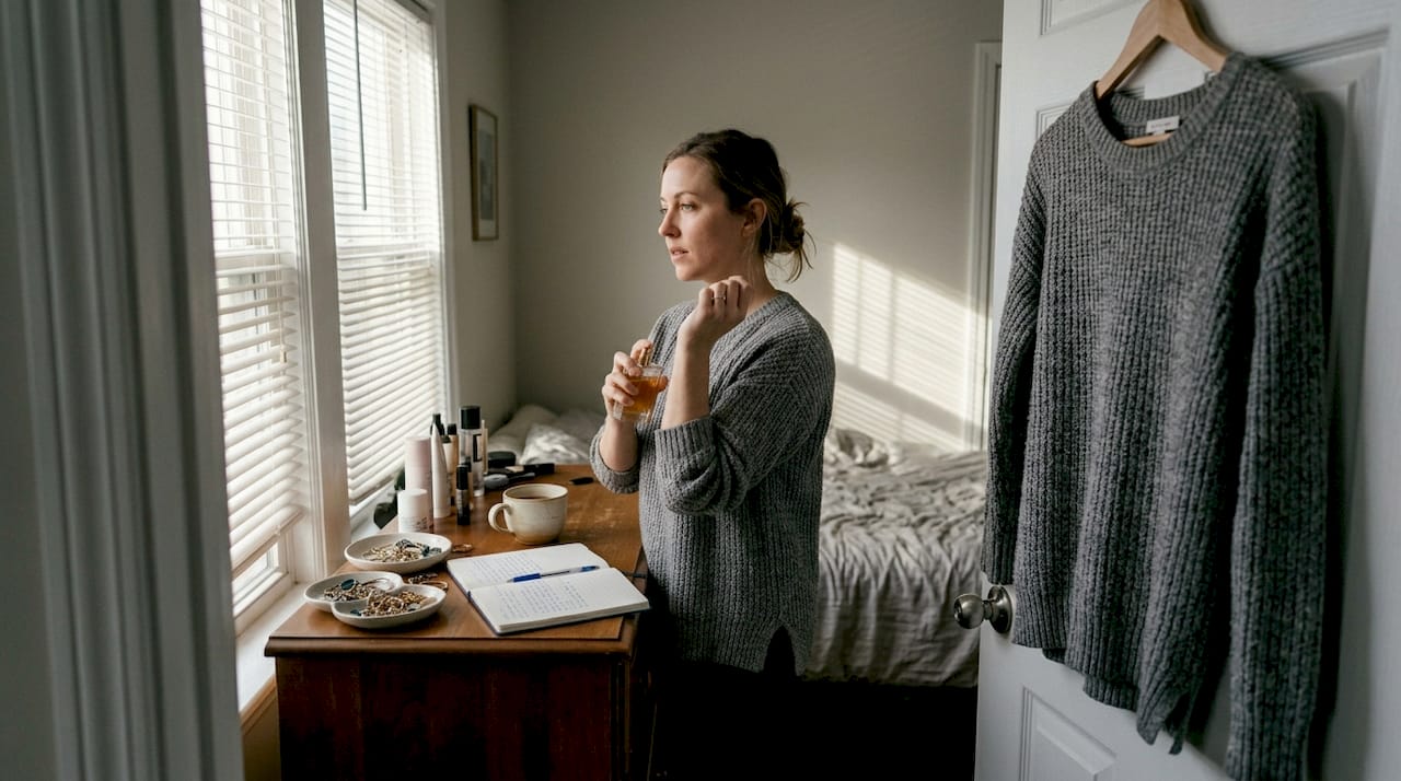 Woman applying perfume in sunny bedroom