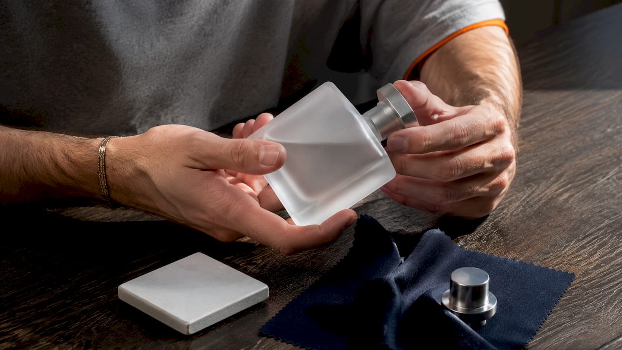 Hands holding premium glass perfume bottle