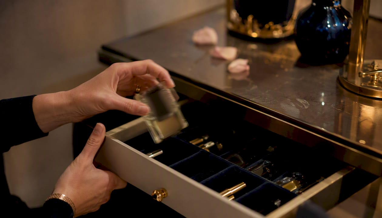 Hands lifting perfume bottle on dressing table