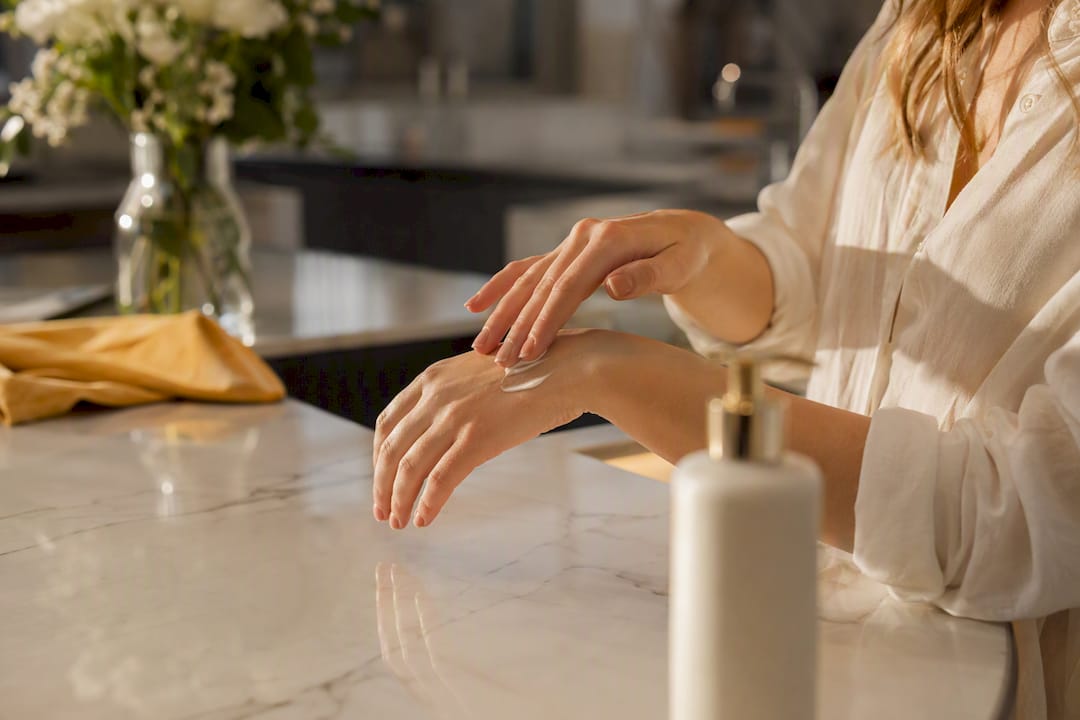 Hands applying scented body lotion