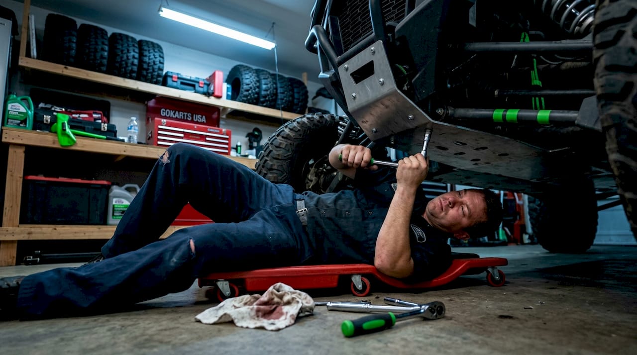 Mechanic installing metal skid plate in garage