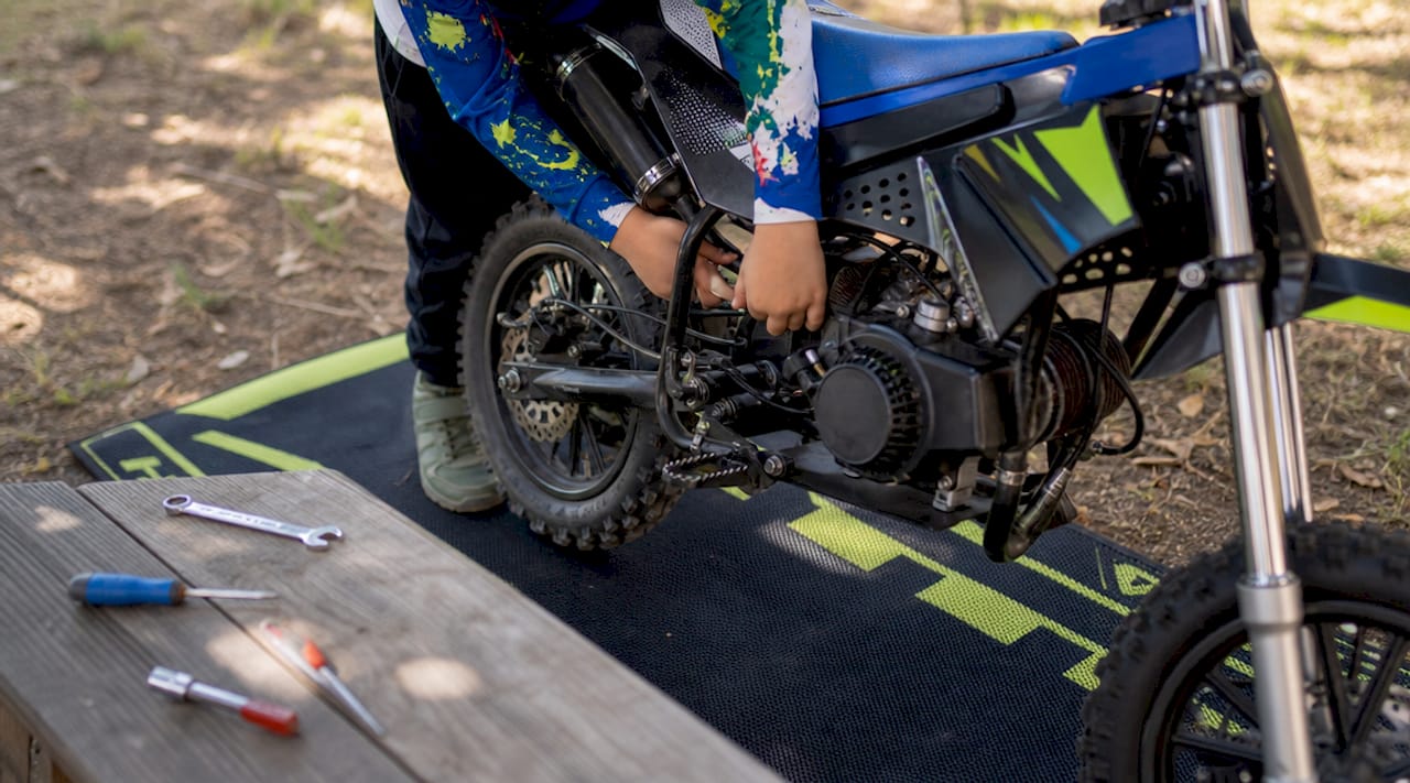 Child's hands examining small dirt bike engine