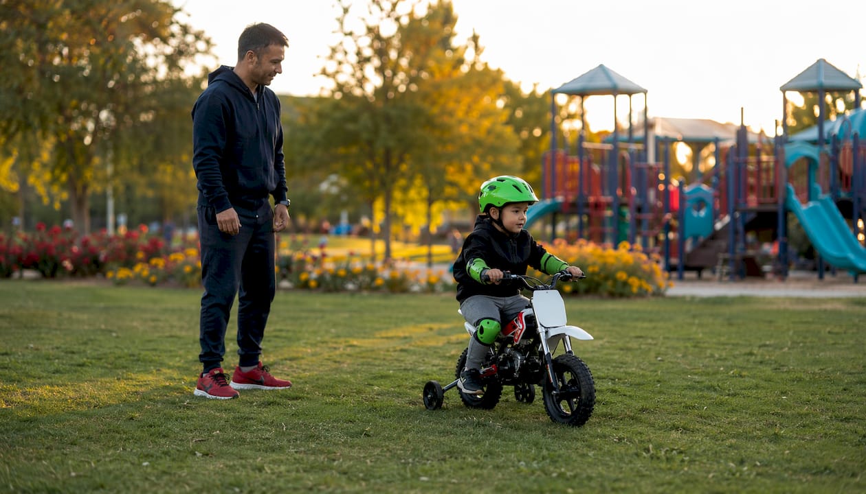 Parent watching child ride minibike with training wheels