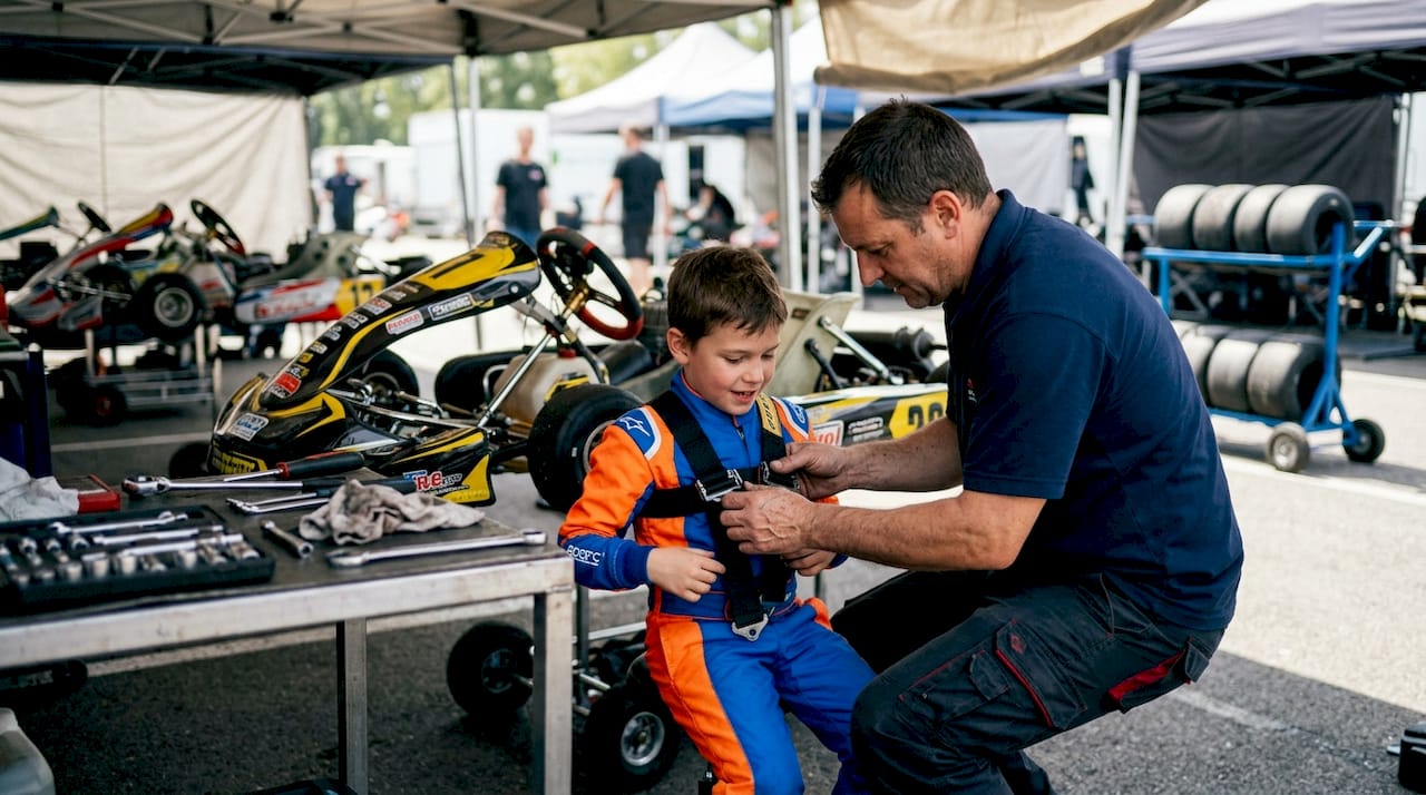 Hands tightening youth kart harness straps outdoors
