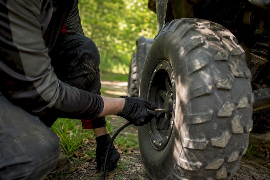Hand adjusting tire pressure on dry trail