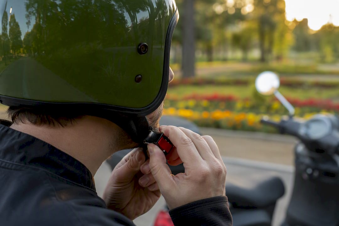 Hands adjusting scooter helmet strap outdoors