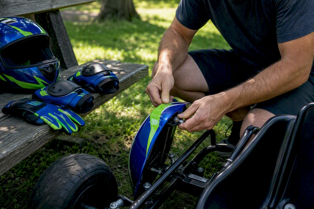 Hands fitting spare tire on child go-kart frame