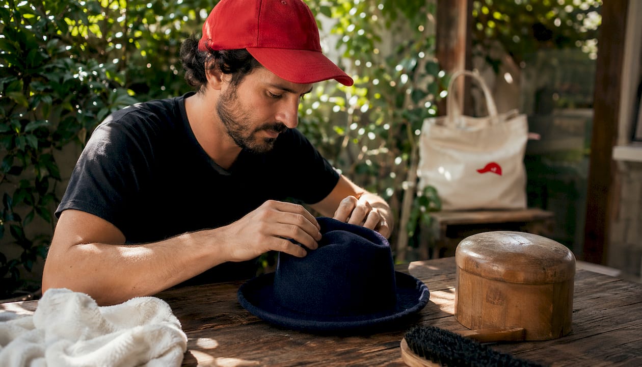 Man reshaping damp wool hat on table