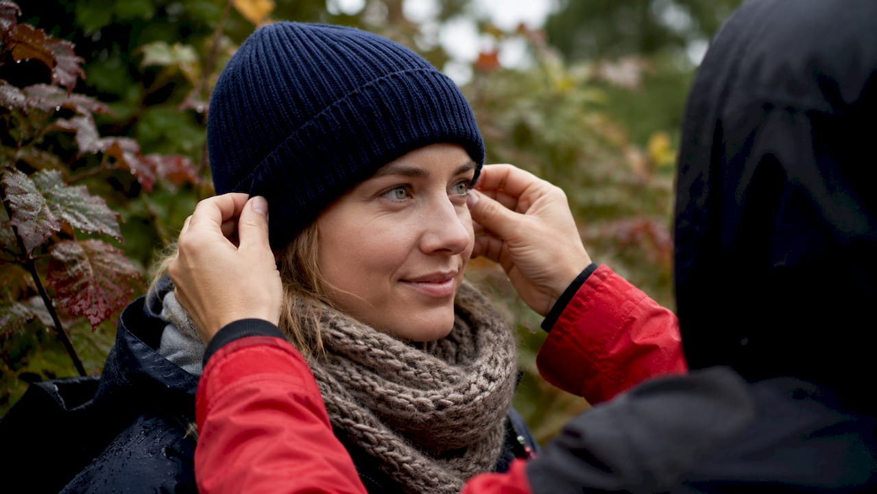 Hands adjusting wool beanie over ears