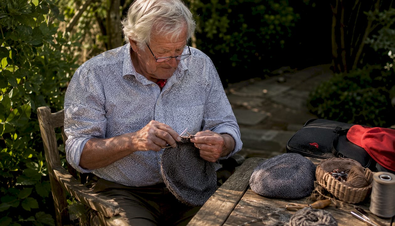 Elderly man knitting a traditional flat cap