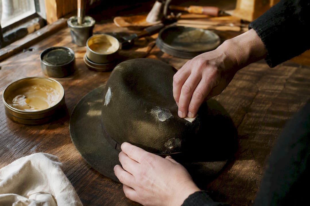 Hands applying wax on wool hat patch