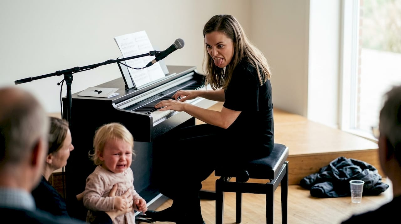 Entertaineren sidder ved klaveret og underholder publikum med både musik og sjove indslag.
