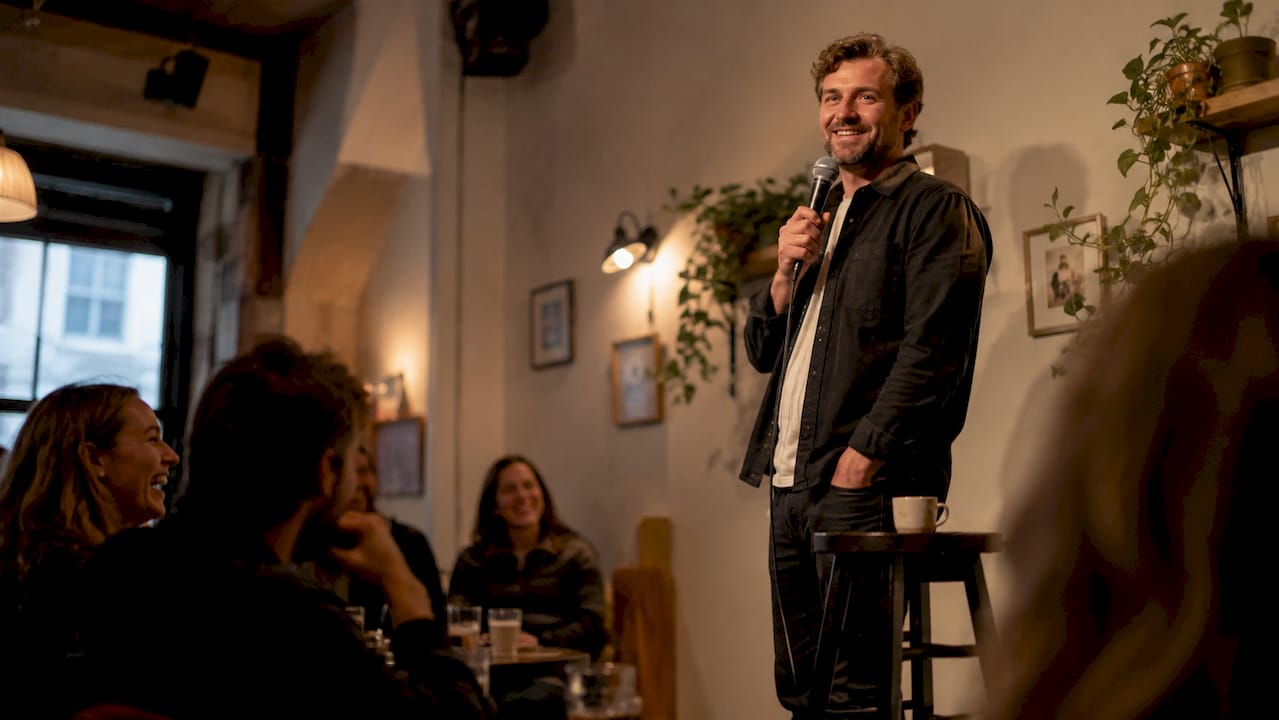En komiker står på scenen og underholder publikum med stand-up