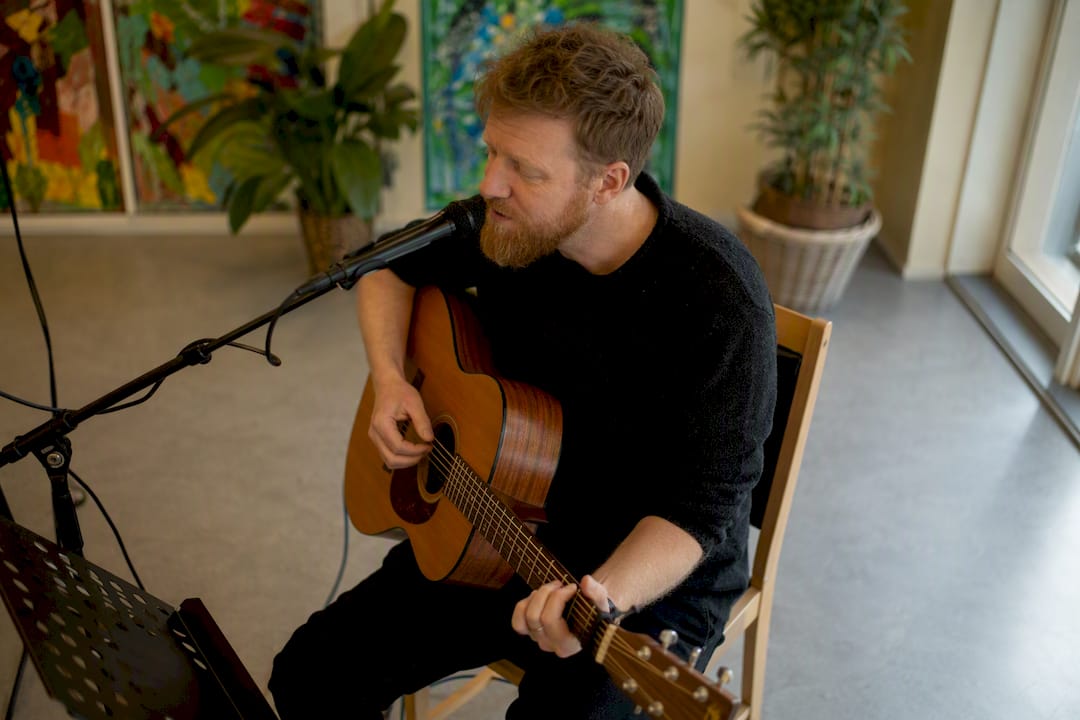 En musiker underholder beboerne på plejehjemmet med guitarspil