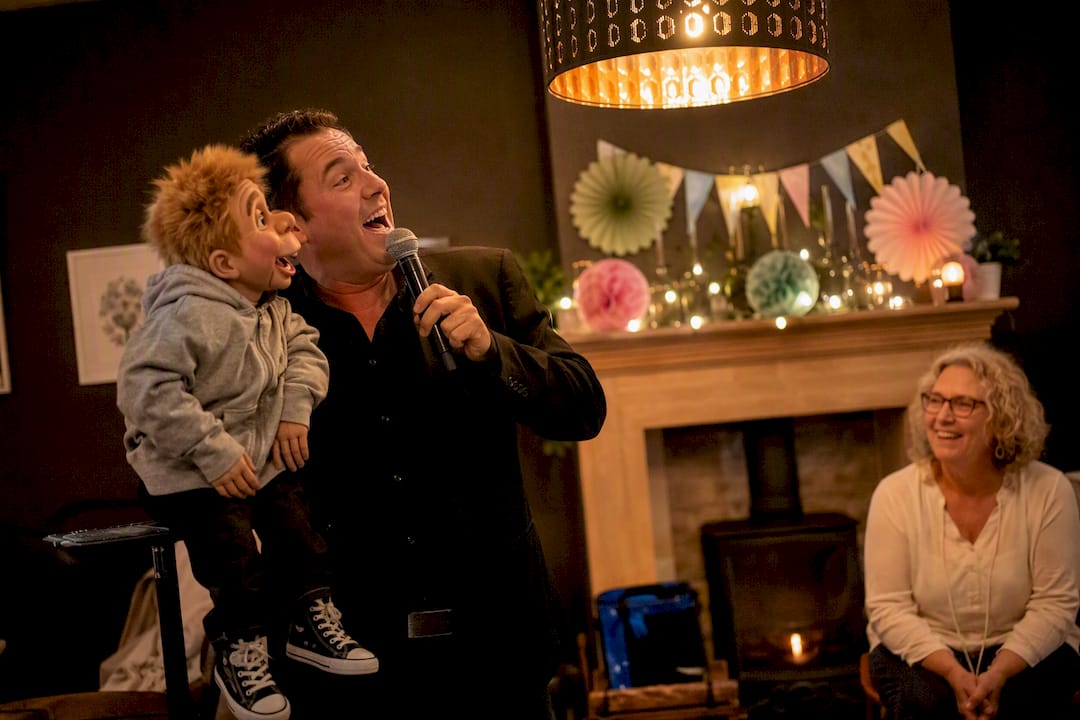 Ventriloquist, der synger med dukke på scenen