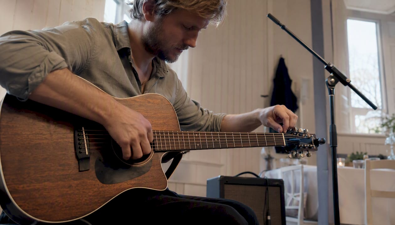 Musiker stemmer sin akustiske guitar før optræden
