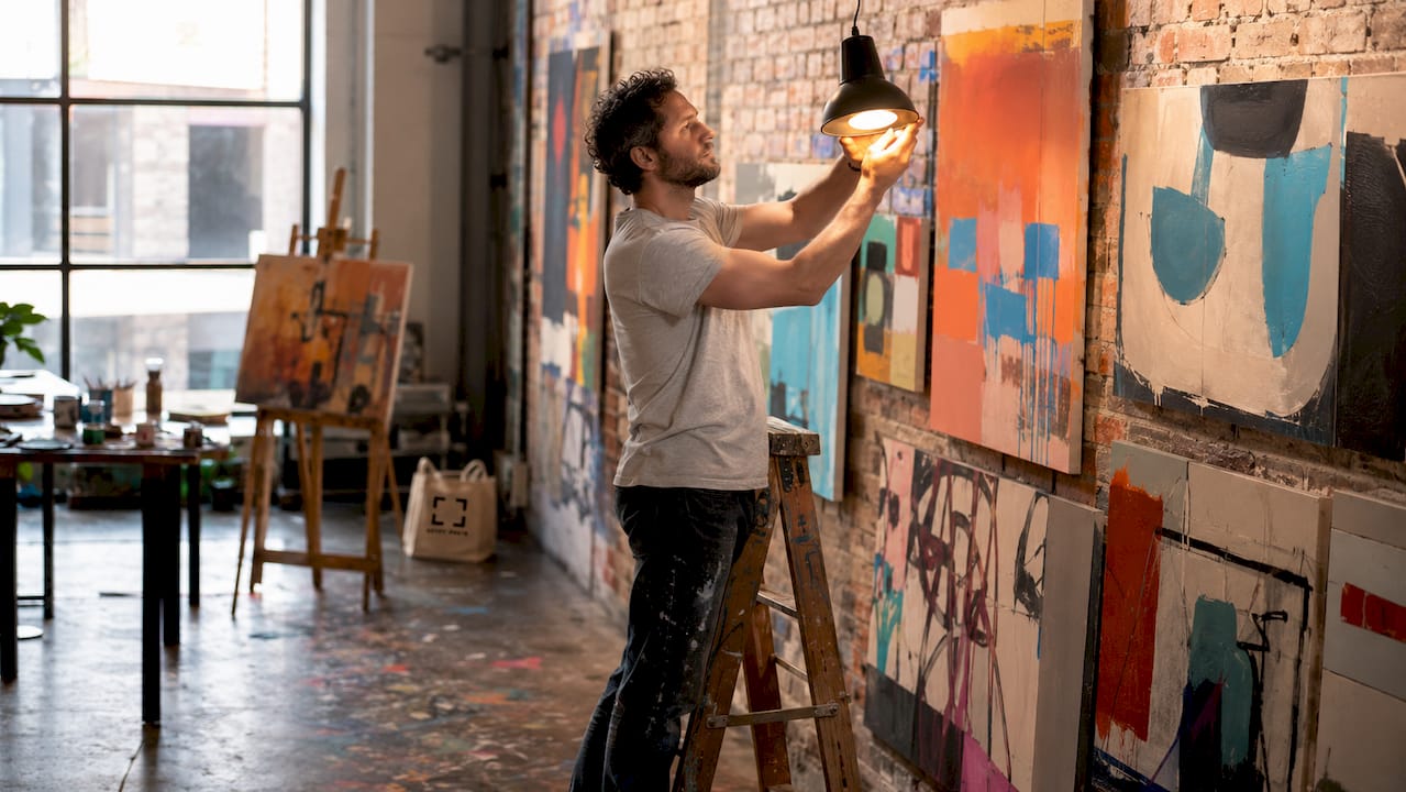 Technician adjusting gallery wall lighting in studio