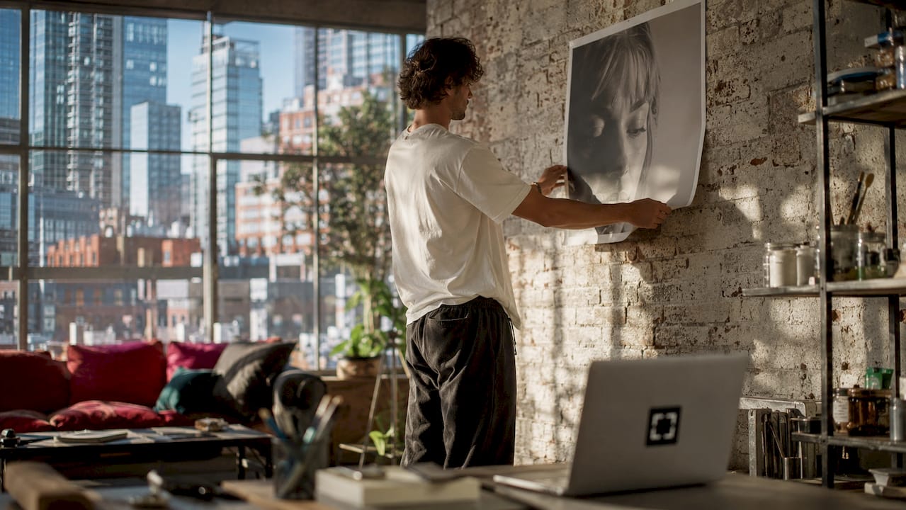 Man visualizing portrait size on blank wall