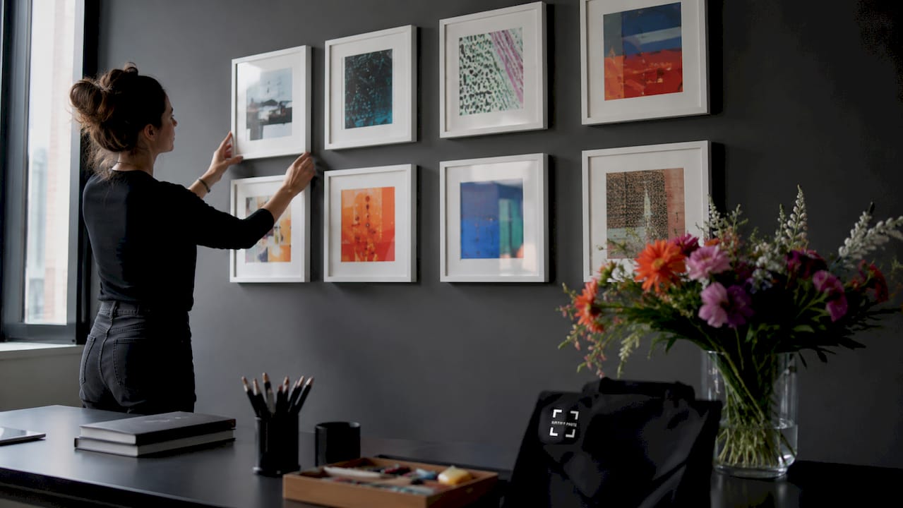 Hands measuring spacing between art frames