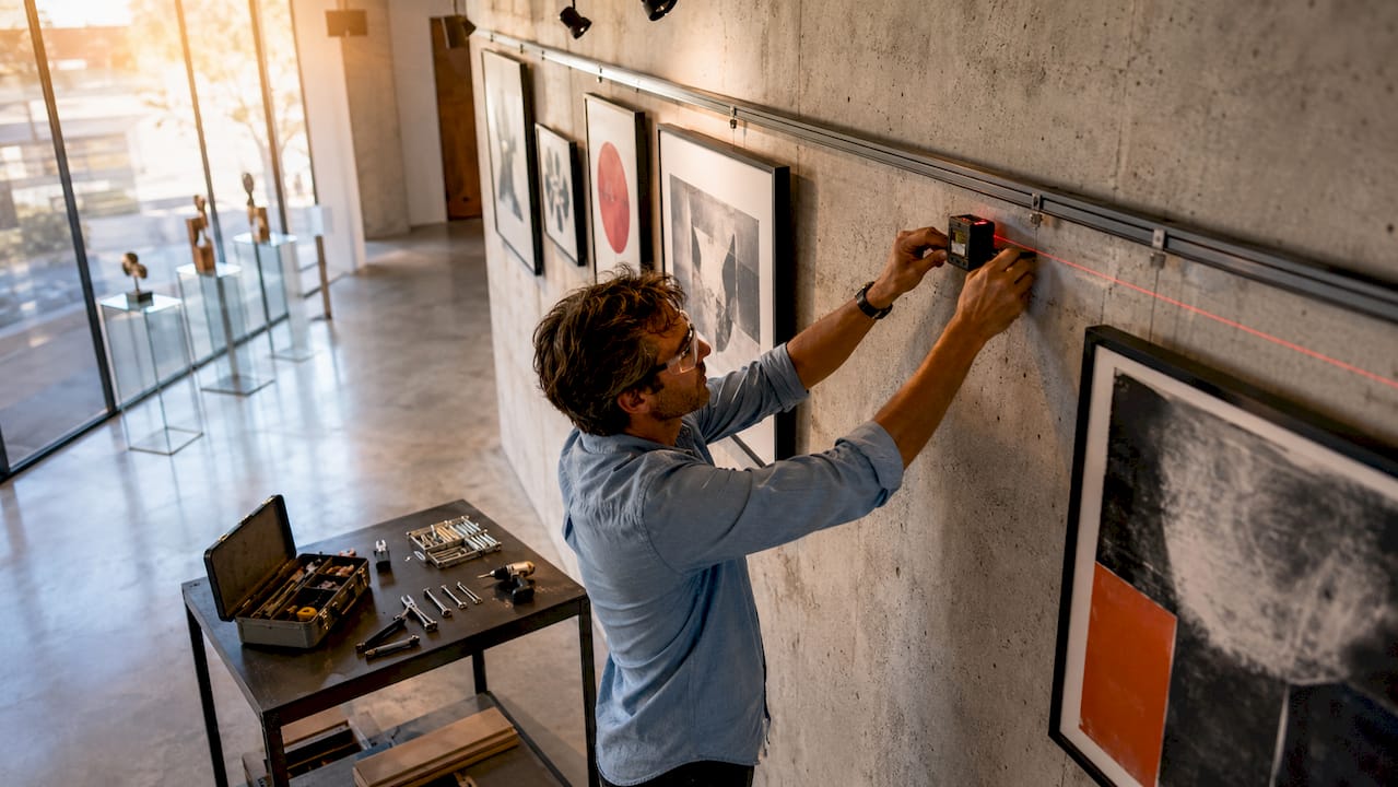 Installer using laser level to hang artwork