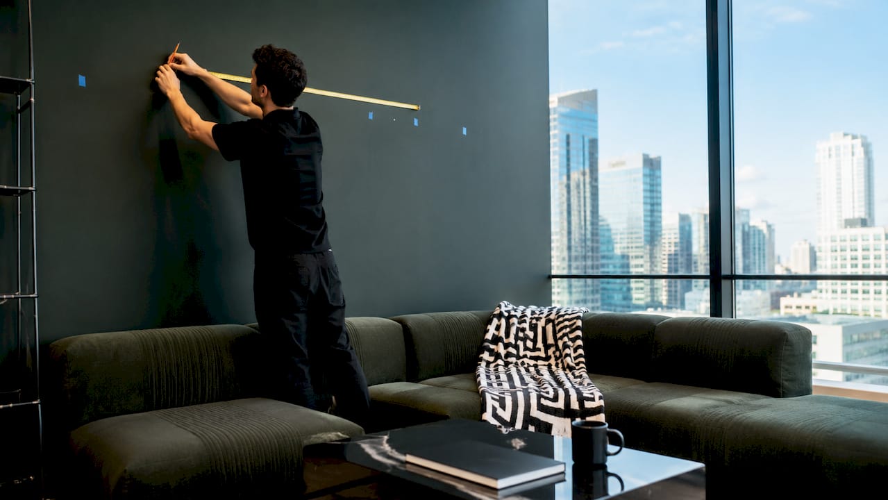 Hands measuring wall space above sofa for art