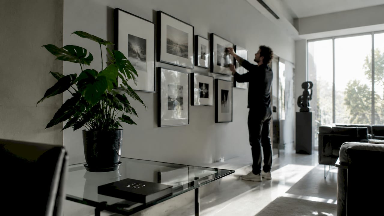 Hands adjusting framed art on gallery wall