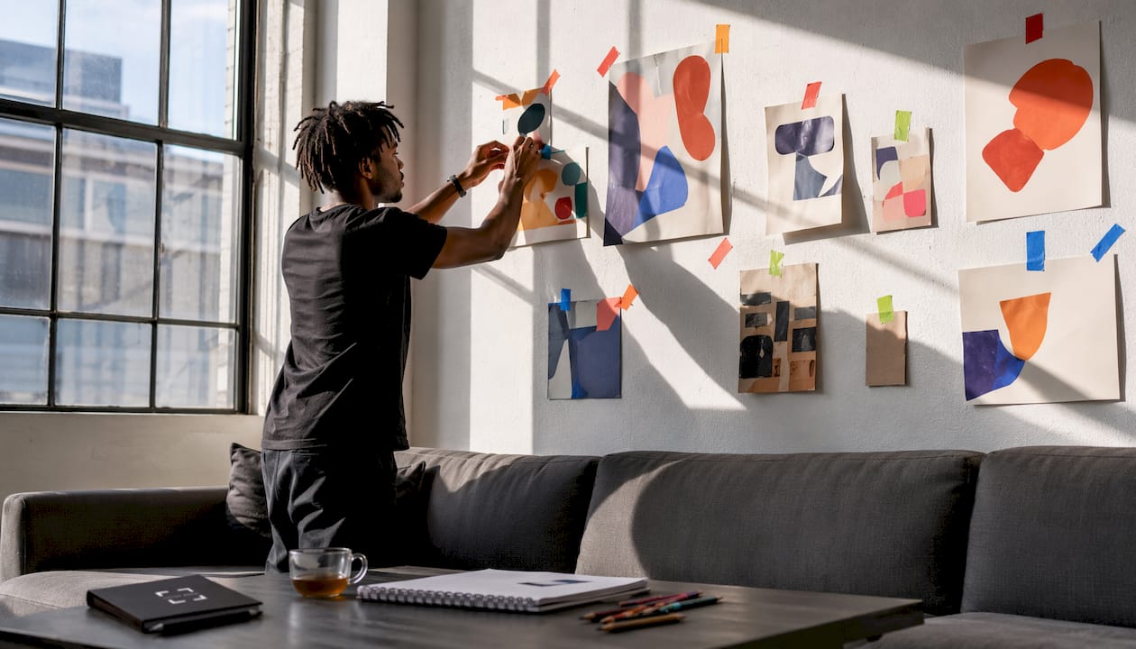 Hands arranging art templates above sofa