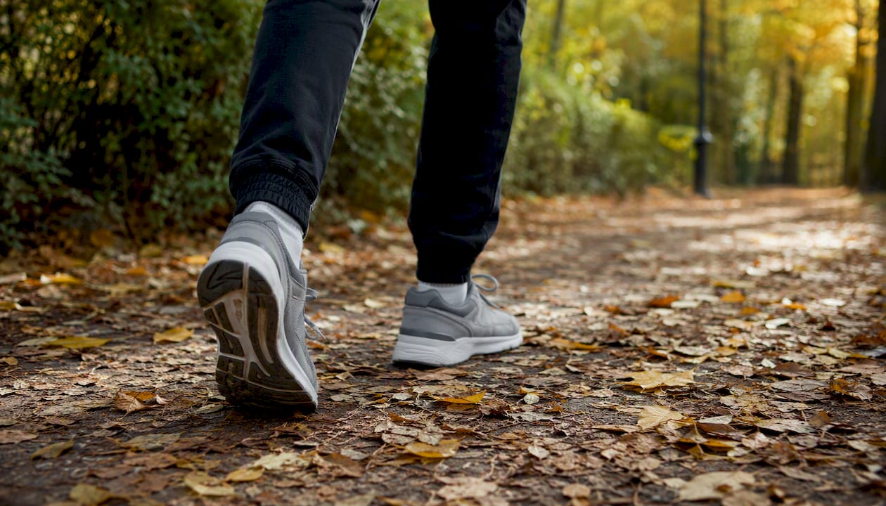 Legs walking briskly on autumn park path