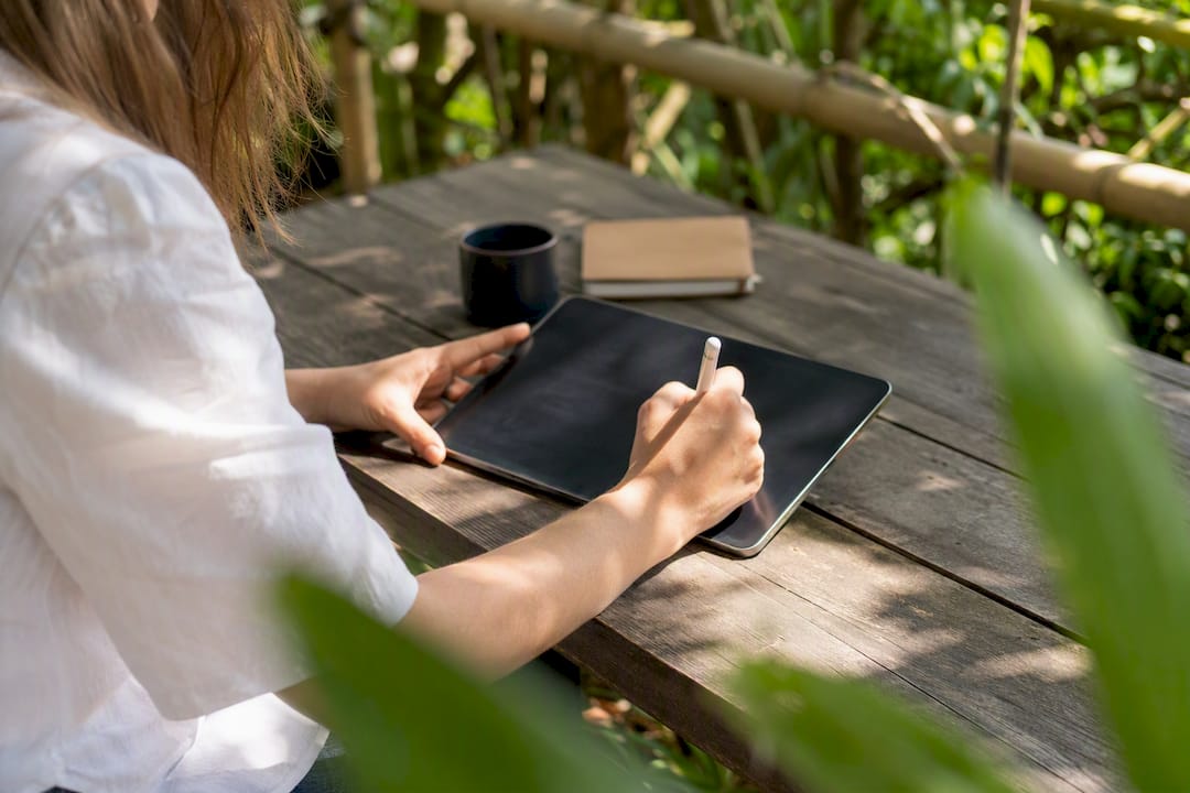 Hands writing email copy notes on tablet