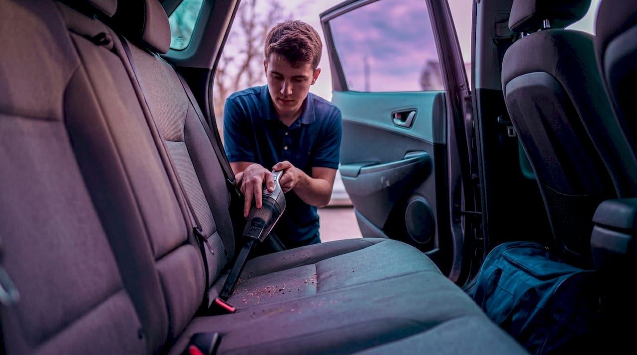 Man vacuuming seams of car fabric seat
