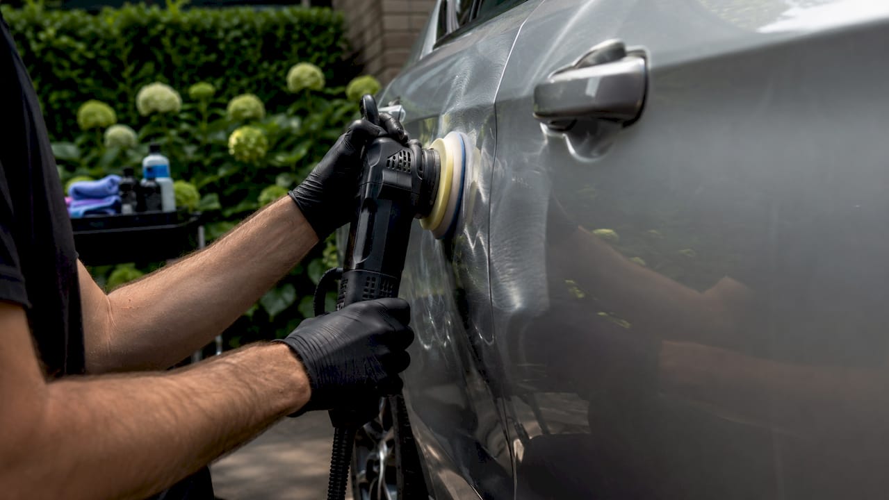 Hands using rotary polisher on car door