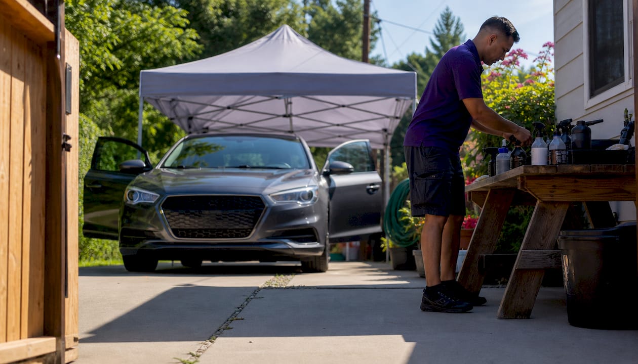 Detailer preparing workspace with open car doors