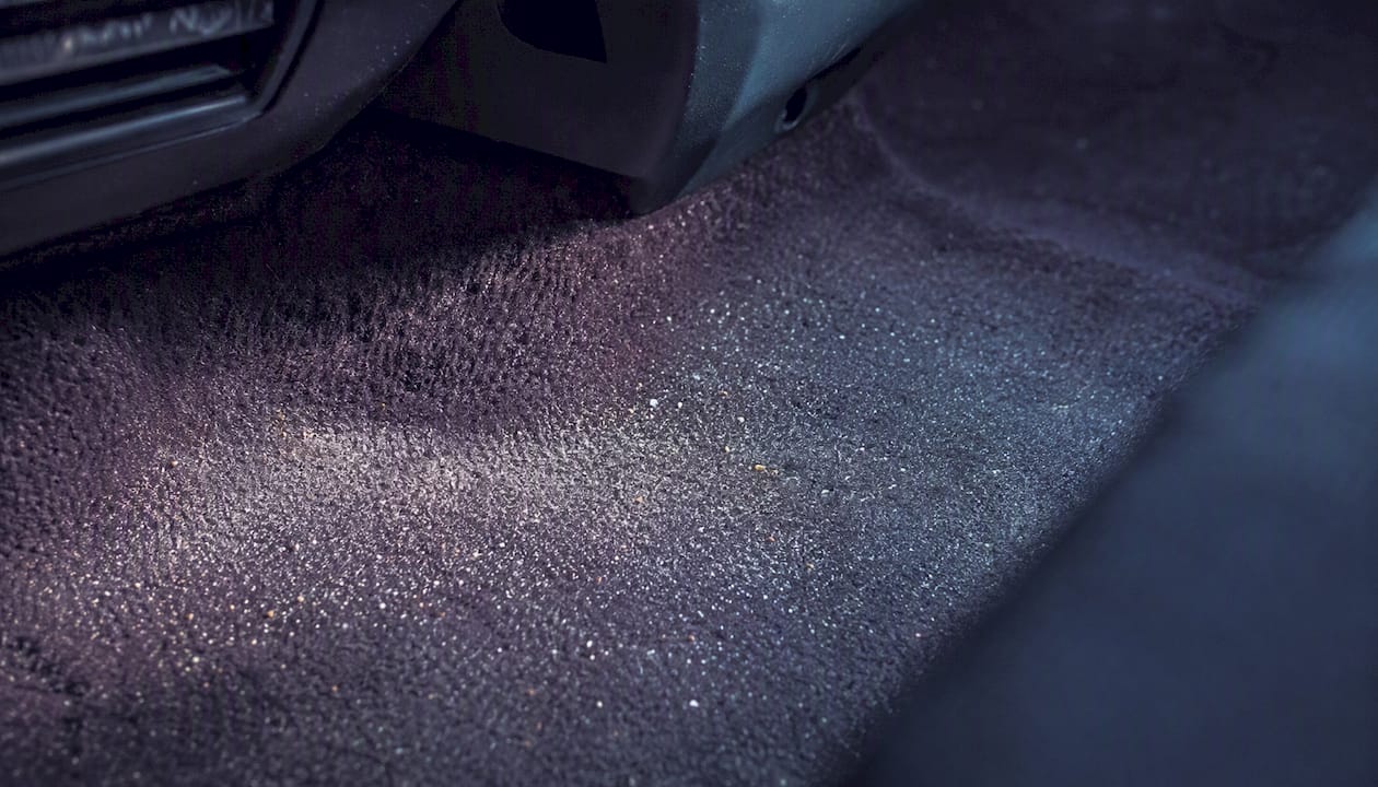 Damp car carpet with embedded sand grains