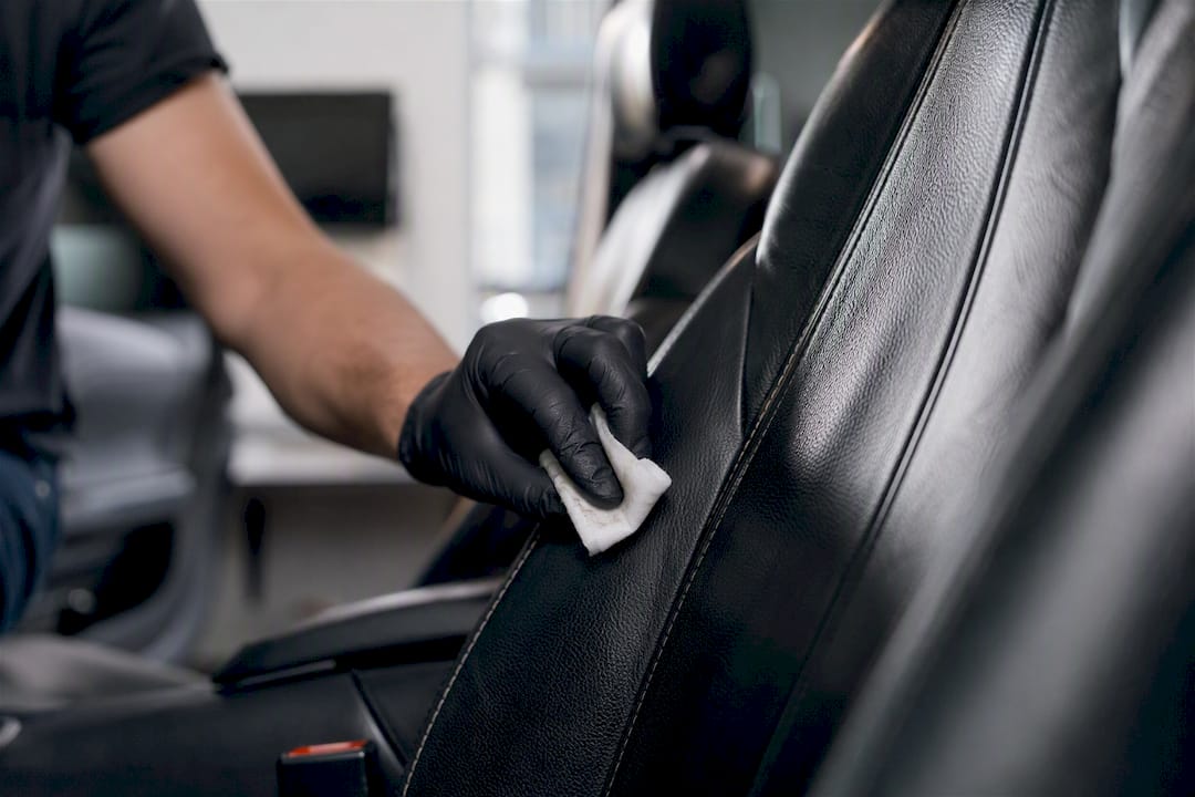 Detailer wiping urine stain on leather car seat seam