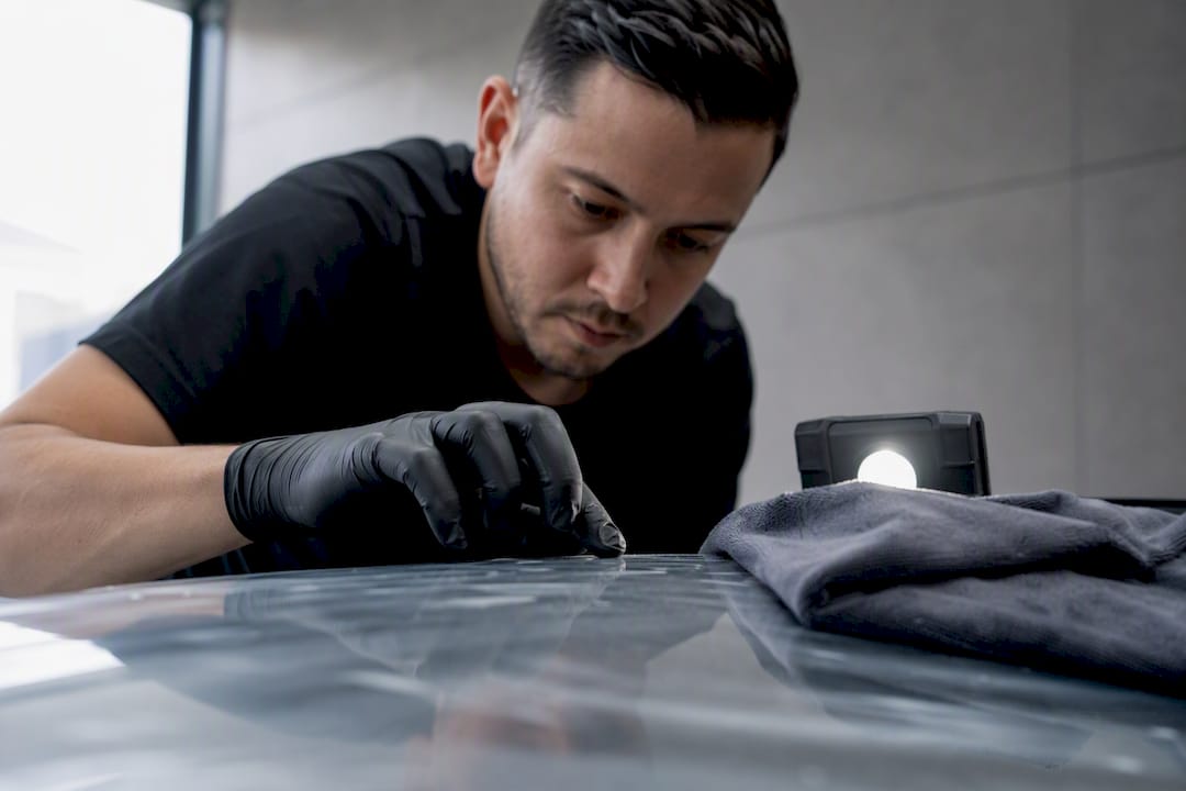 Detailer inspecting coating compatibility on PPF