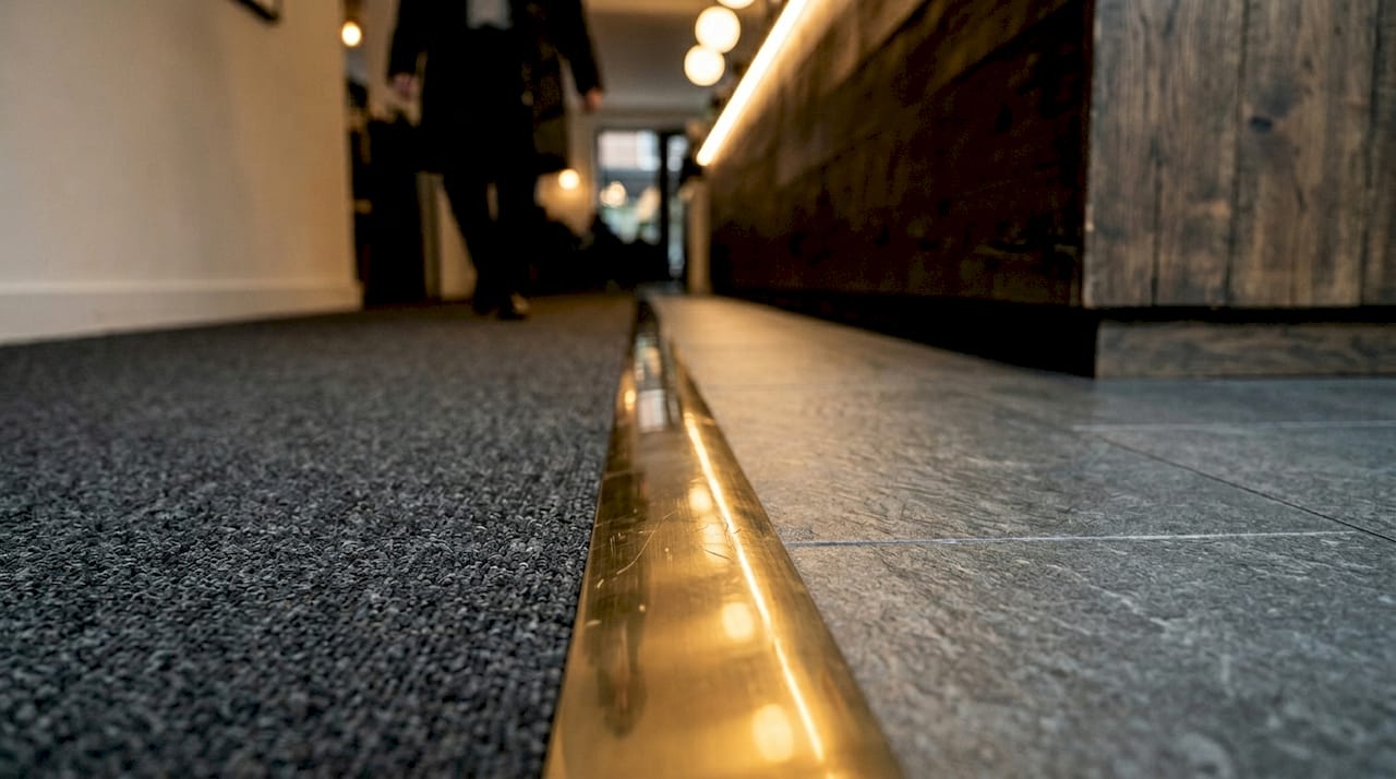 Close-up of brass trim between carpet and tile