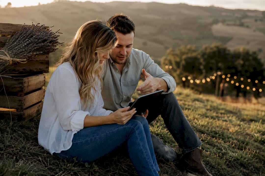 Couple choosing electronic wedding invitations outdoors